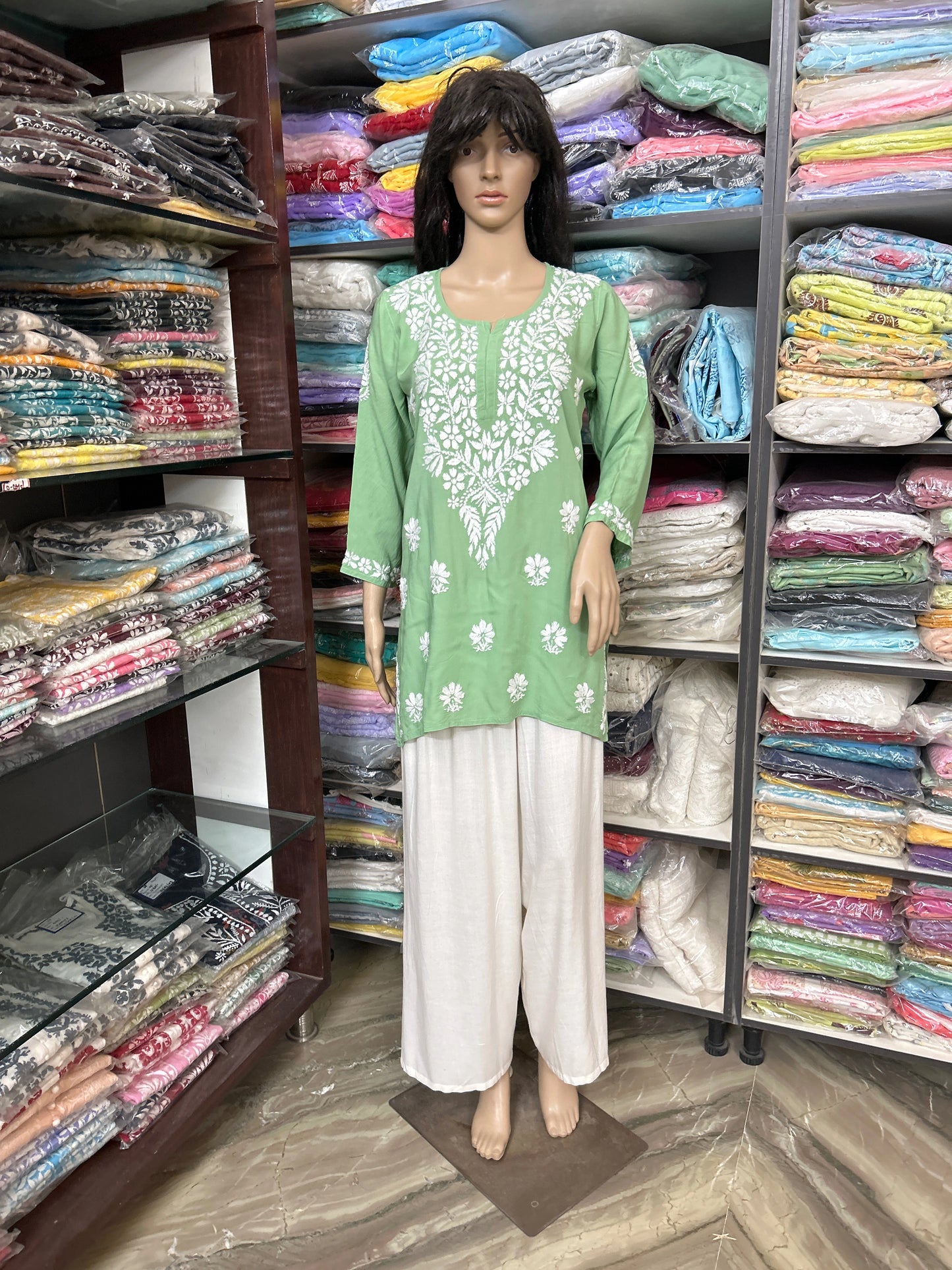 lucknowi chikankari Mannequin wearing a green and white outfit in a fabric store