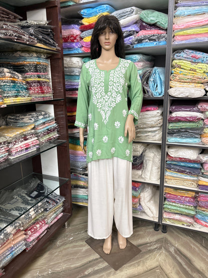 lucknowi chikankari Mannequin wearing a green and white outfit in a fabric store
