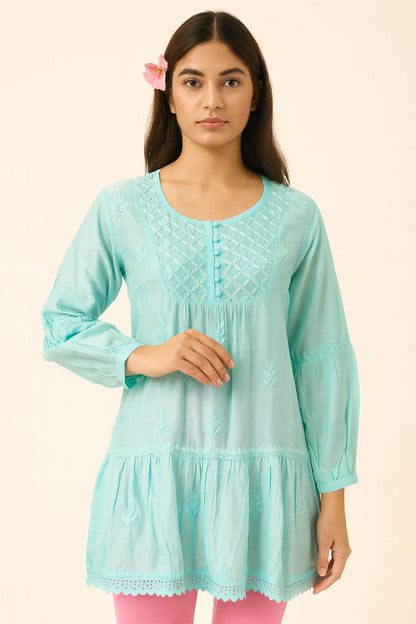 Woman wearing a light blue embroidered kurta with pink pants on a beige background