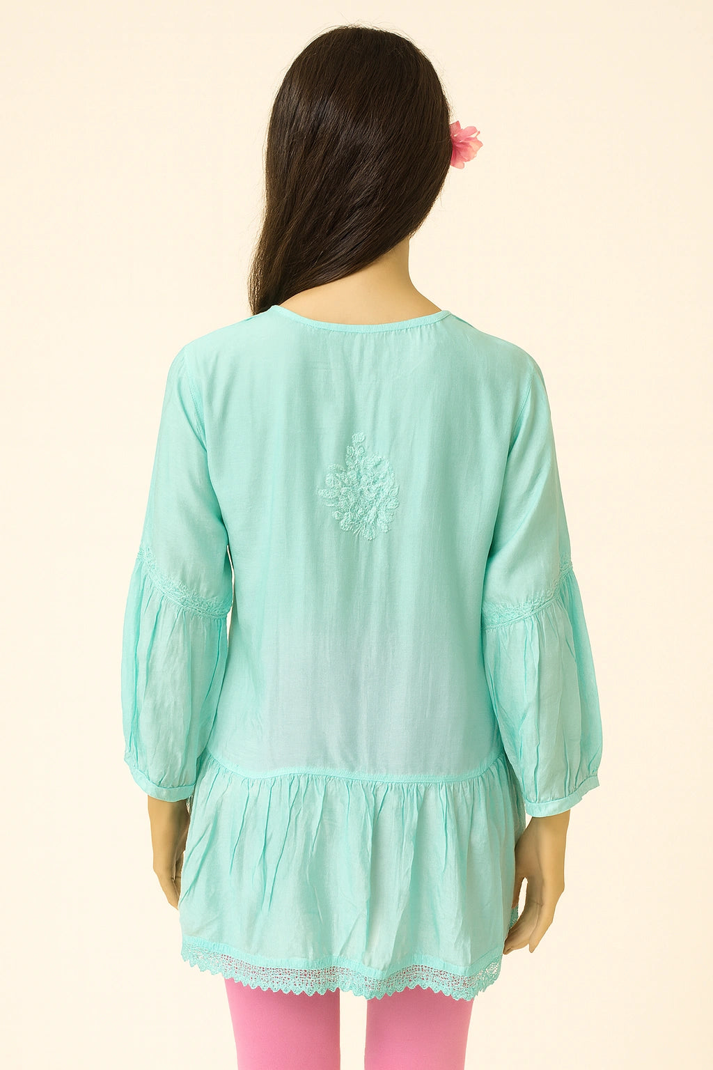 Person wearing a lucknowi chikankari light blue top with a subtle pattern on a beige background