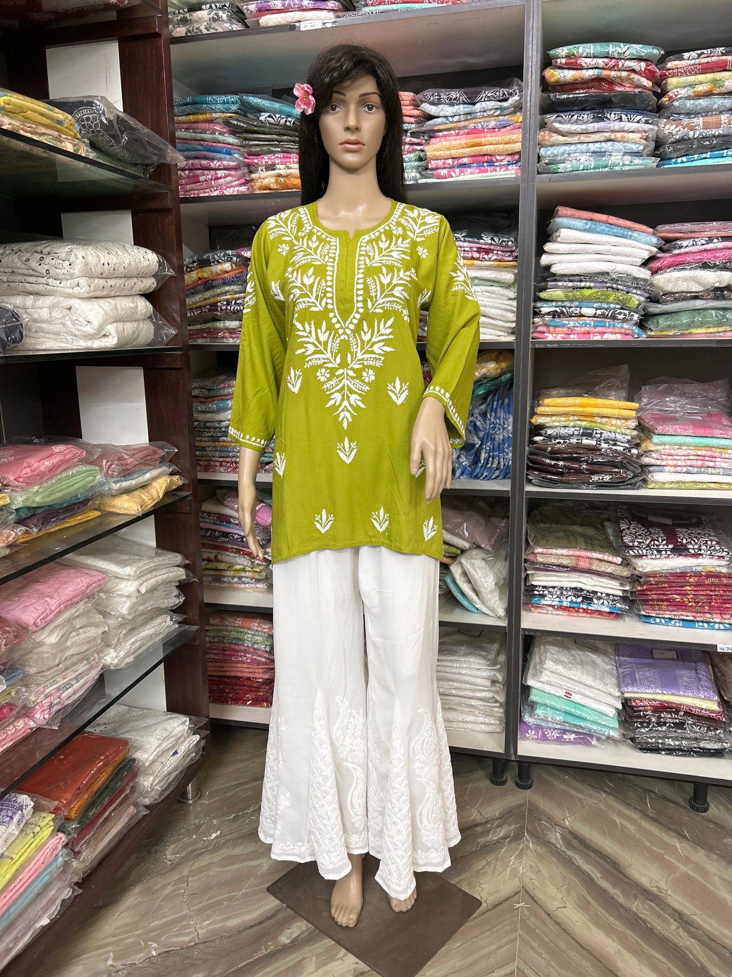 Mannequin wearing a lucknowi chikankari green and white outfit in a fabric store