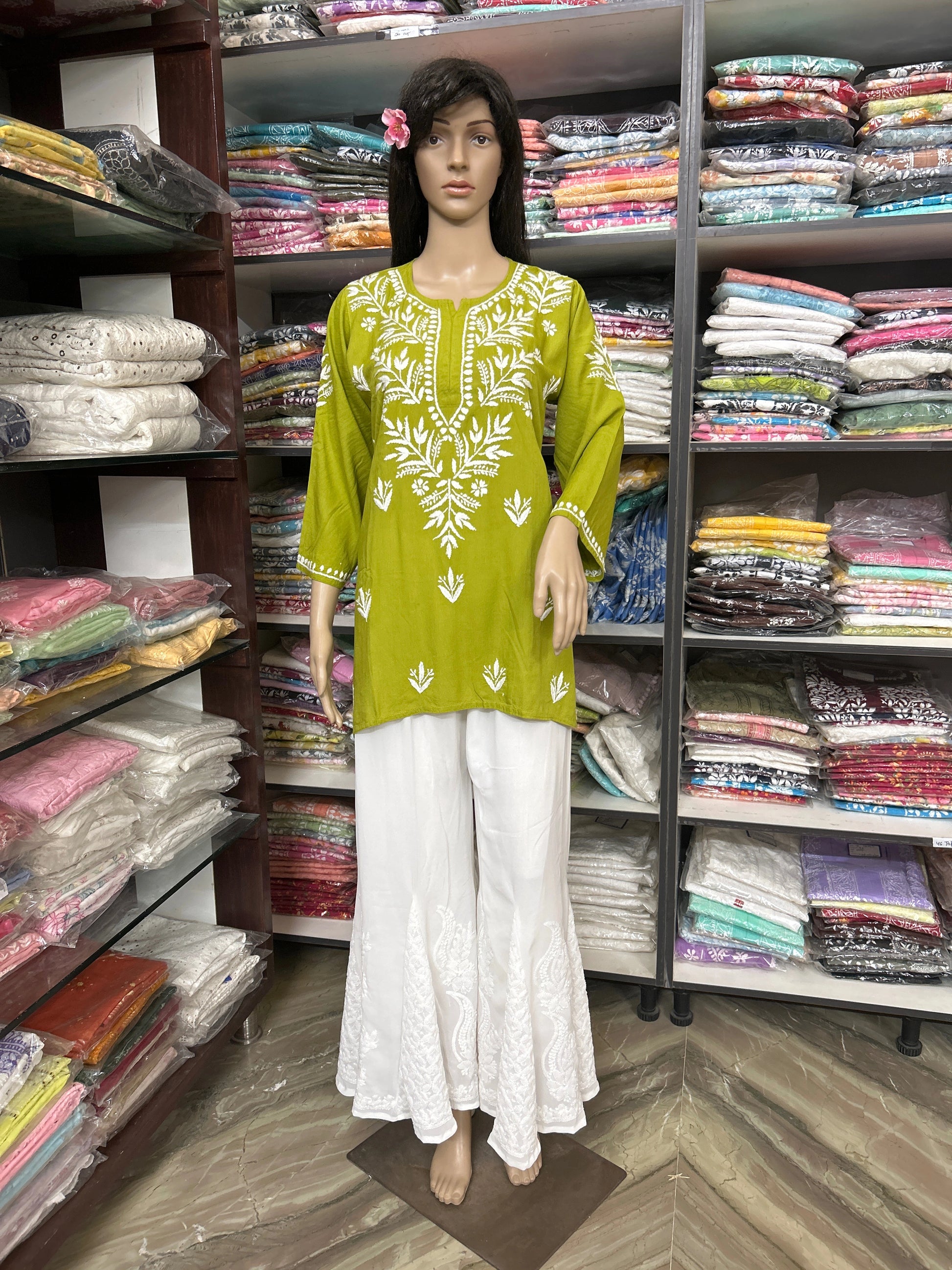 Mannequin wearing a lucknowi chikankari green and white outfit in a fabric store
