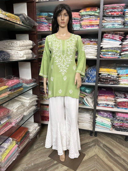 Mannequin wearing a lucknowi chikankari green top and white pants in a fabric store.