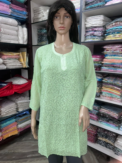 Woman wearing a lucknowi chikankari green-colored kurta with white patterns on a white background