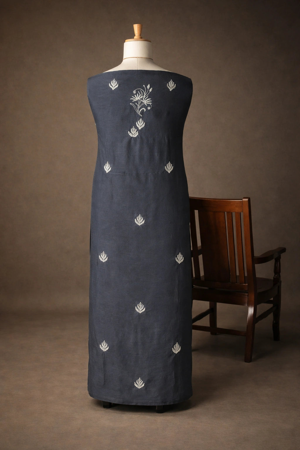 Navy blue dress with white floral embroidery on a mannequin against a brown background