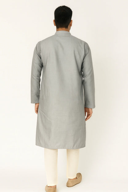 Man wearing a lucknowi chikankari  gray kurta with white pants on a light beige background