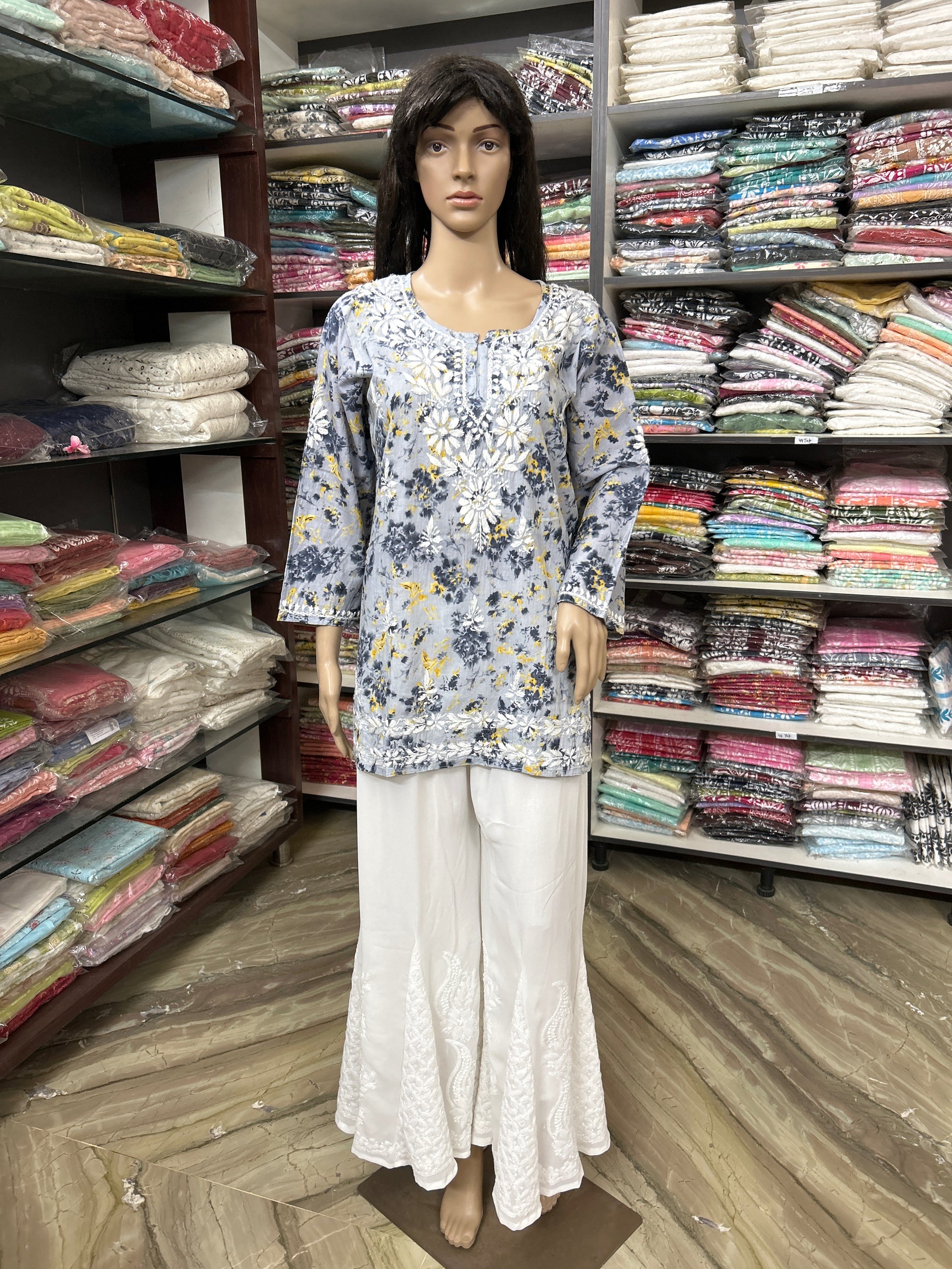 Mannequin wearing a lucknowi chikankari floral top and white pants in a fabric store.