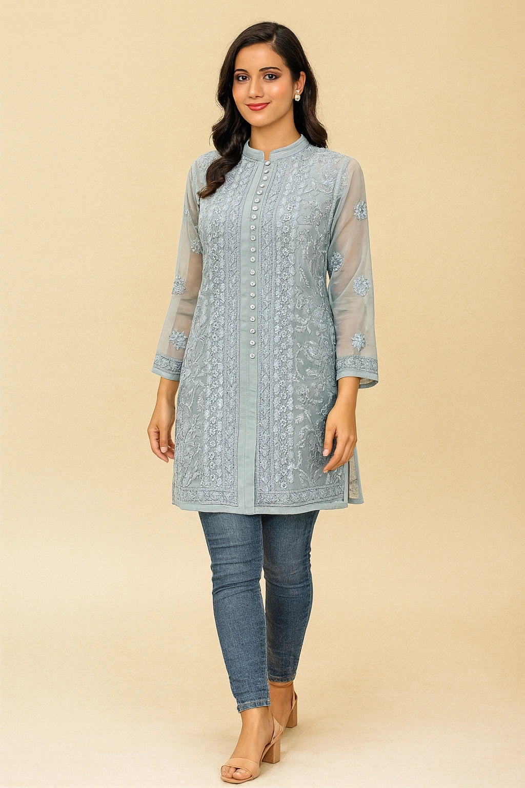 Woman wearing a light blue embroidered kurta with jeans on a beige background