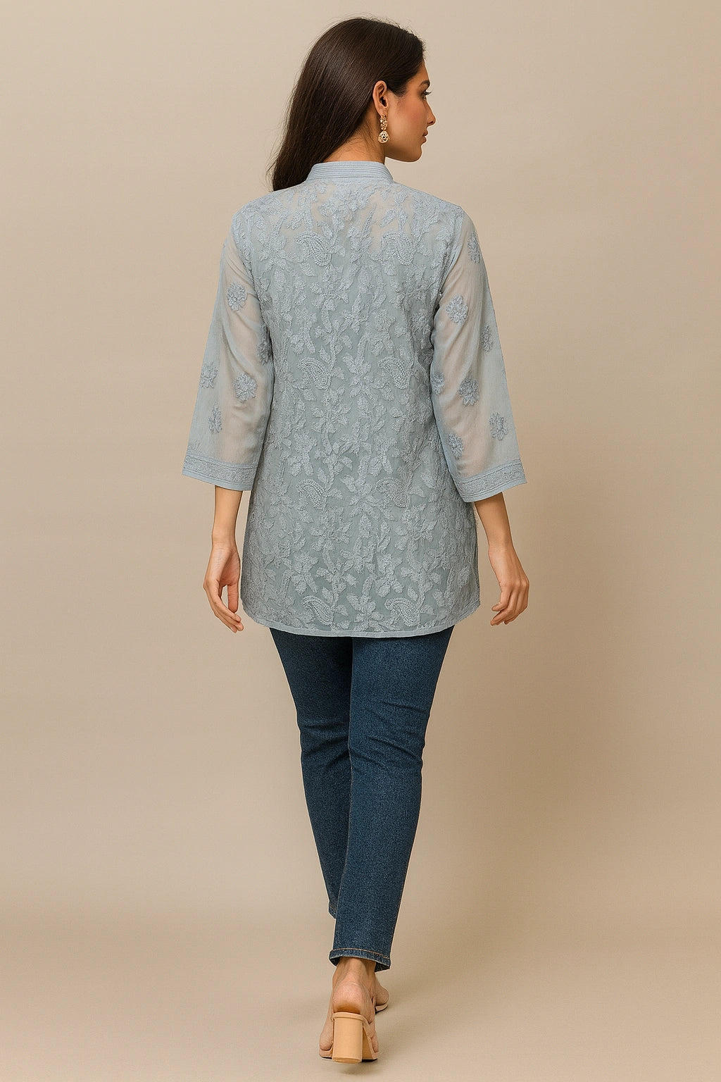 lucknowi chikankari Woman wearing a light blue floral patterned shirt and dark blue jeans on a beige background
