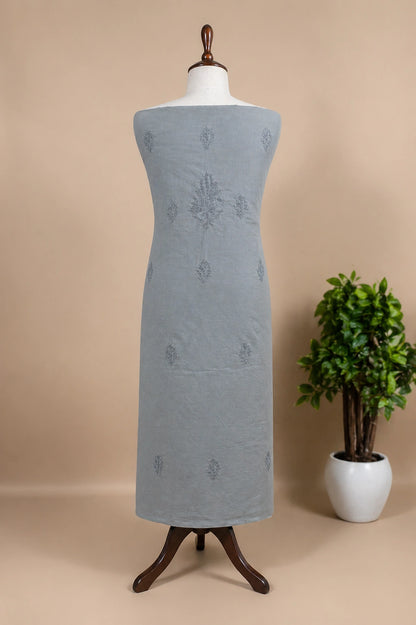 Gray dress on a mannequin with a beige background and a potted plant.
