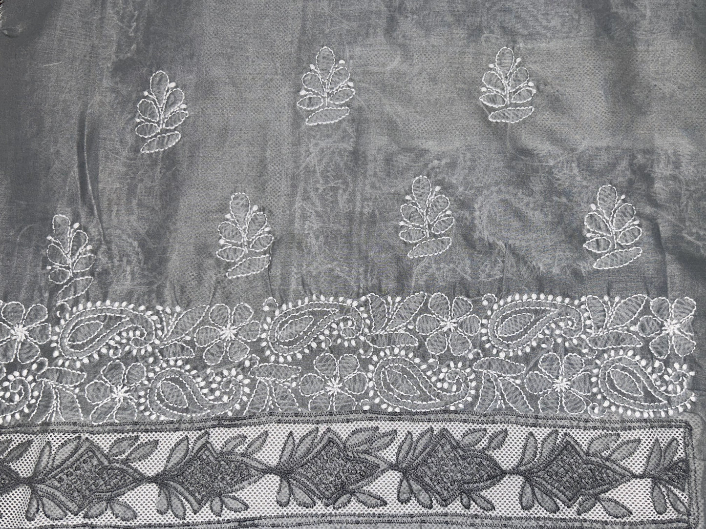 Decorative fabric with intricate white embroidery on a dark background