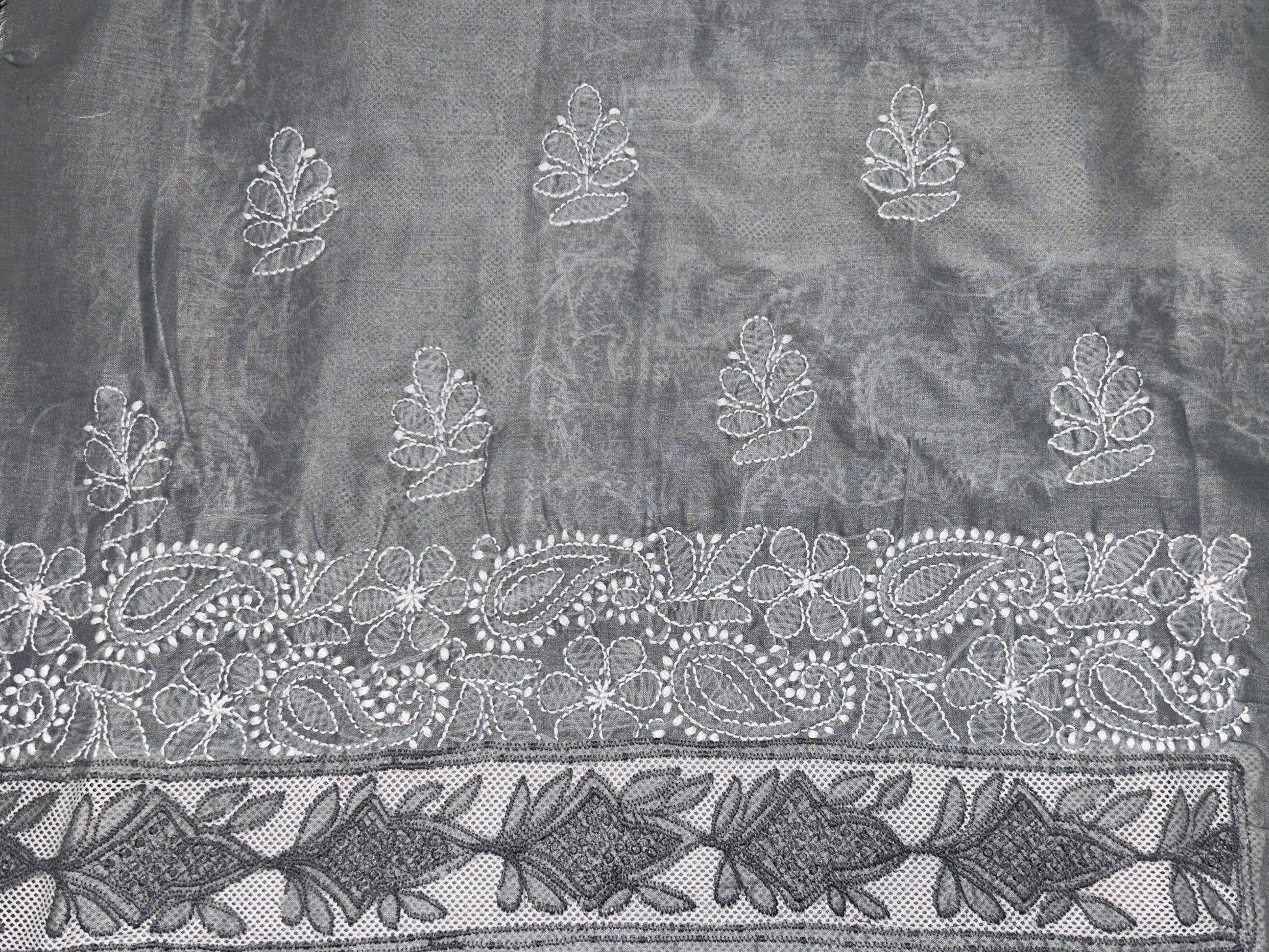 Decorative fabric with intricate white embroidery on a dark background