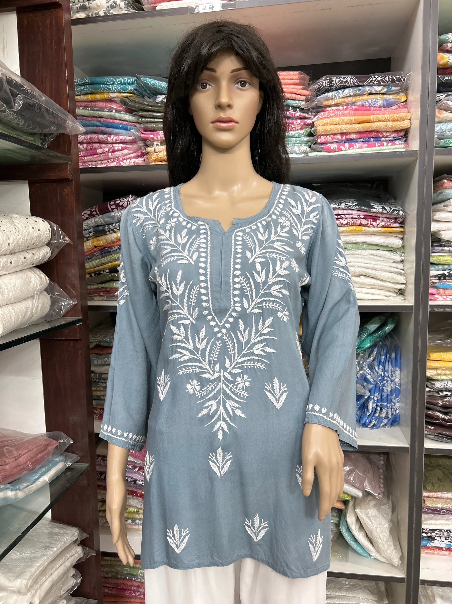 Mannequin wearing a blue embroidered top in a fabric store