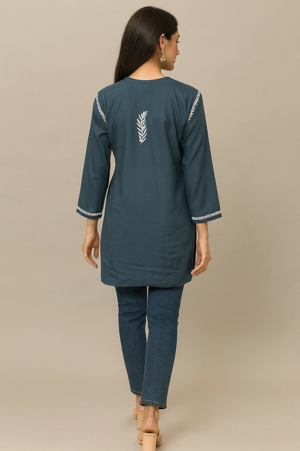 Woman wearing a teal kurta with white embroidery on a beige background