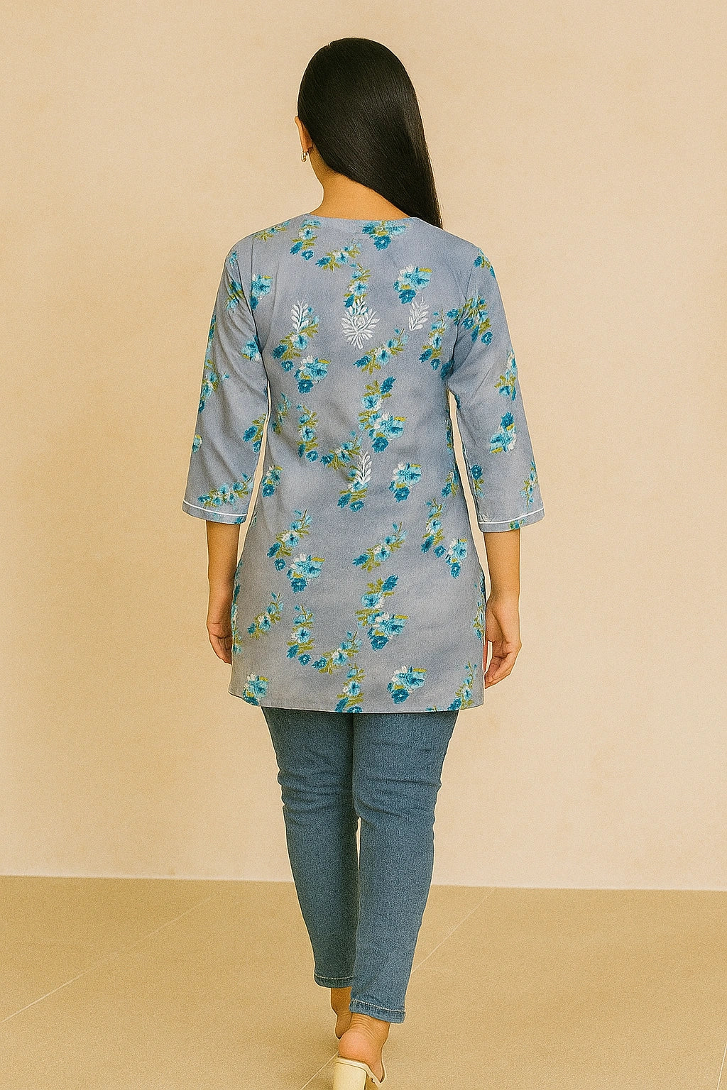 Woman wearing a lucknowi chikankari grey top with white polka dots and blue jeans on a gray background