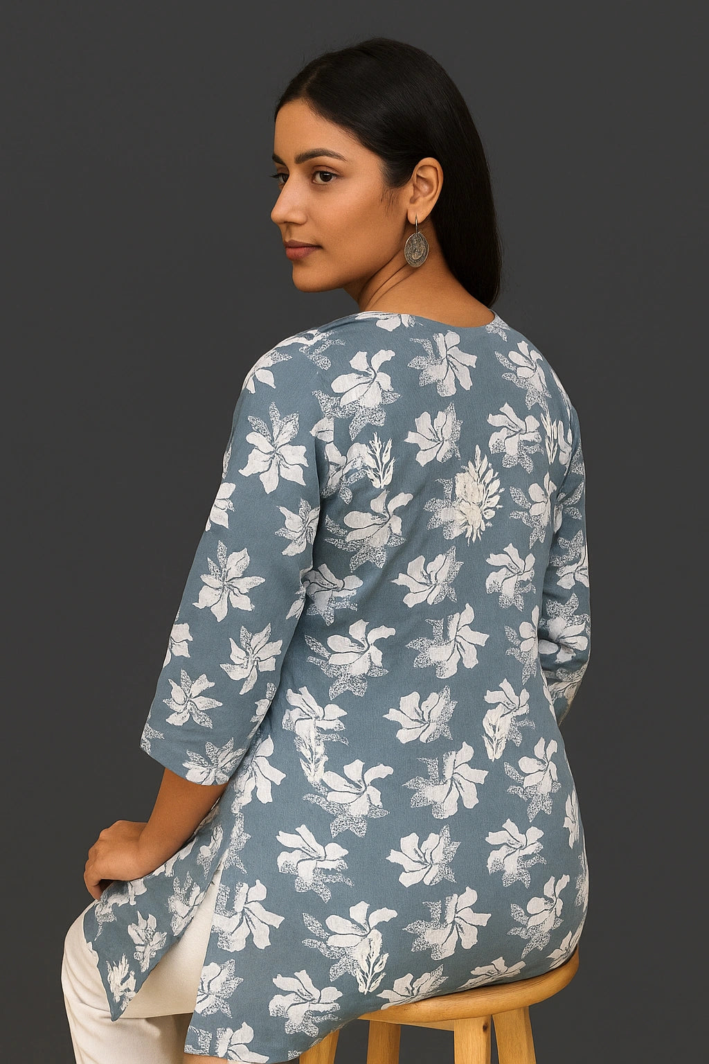 Woman wearing a lucknowi chikankari grey top with white polka dots and blue jeans on a gray background