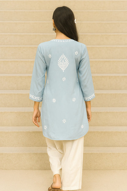 Light blue embroidered kurta worn by a person on a beige staircase