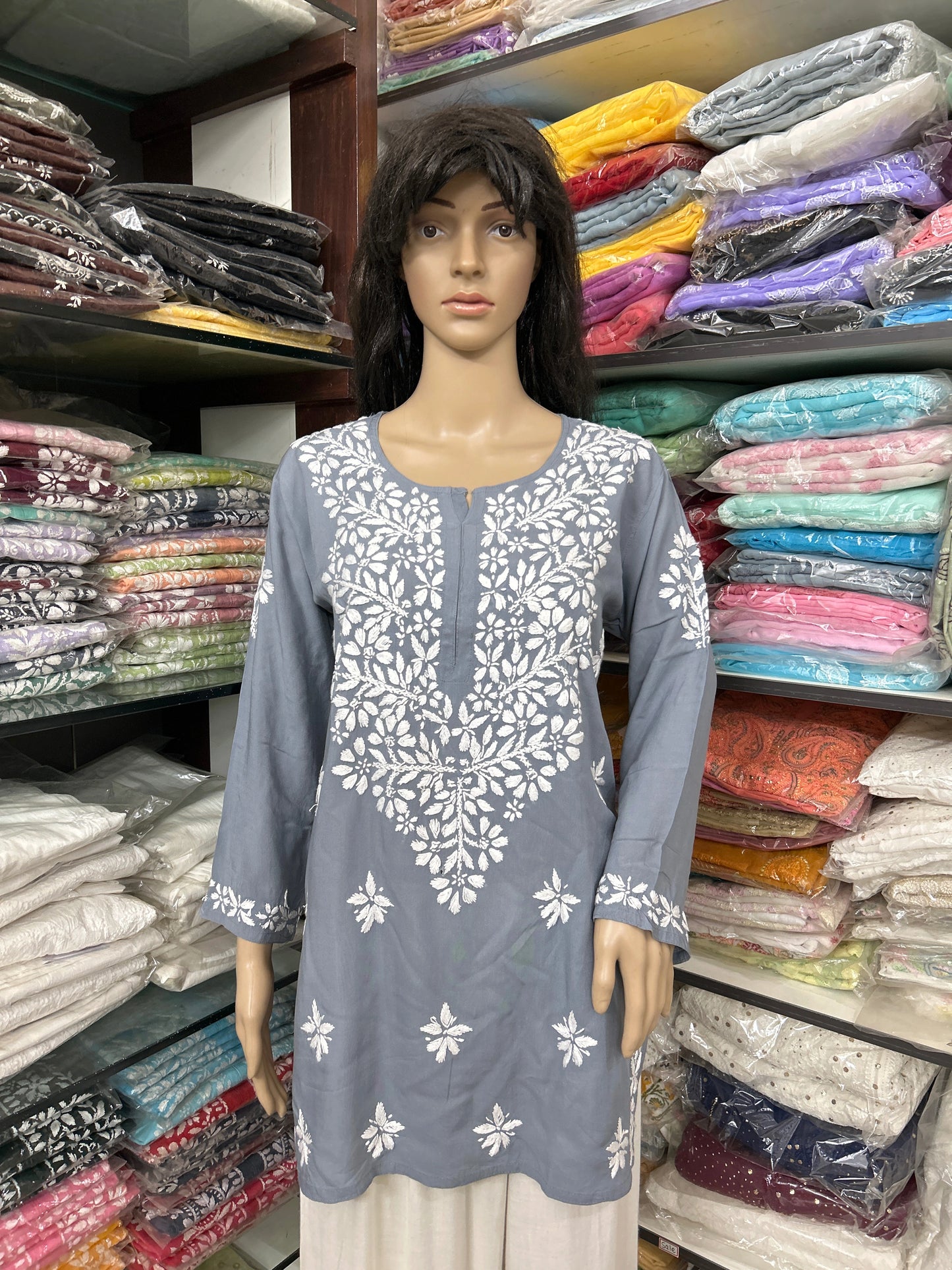 Mannequin wearing a lucknowi chikankari grey top in a fabric store.