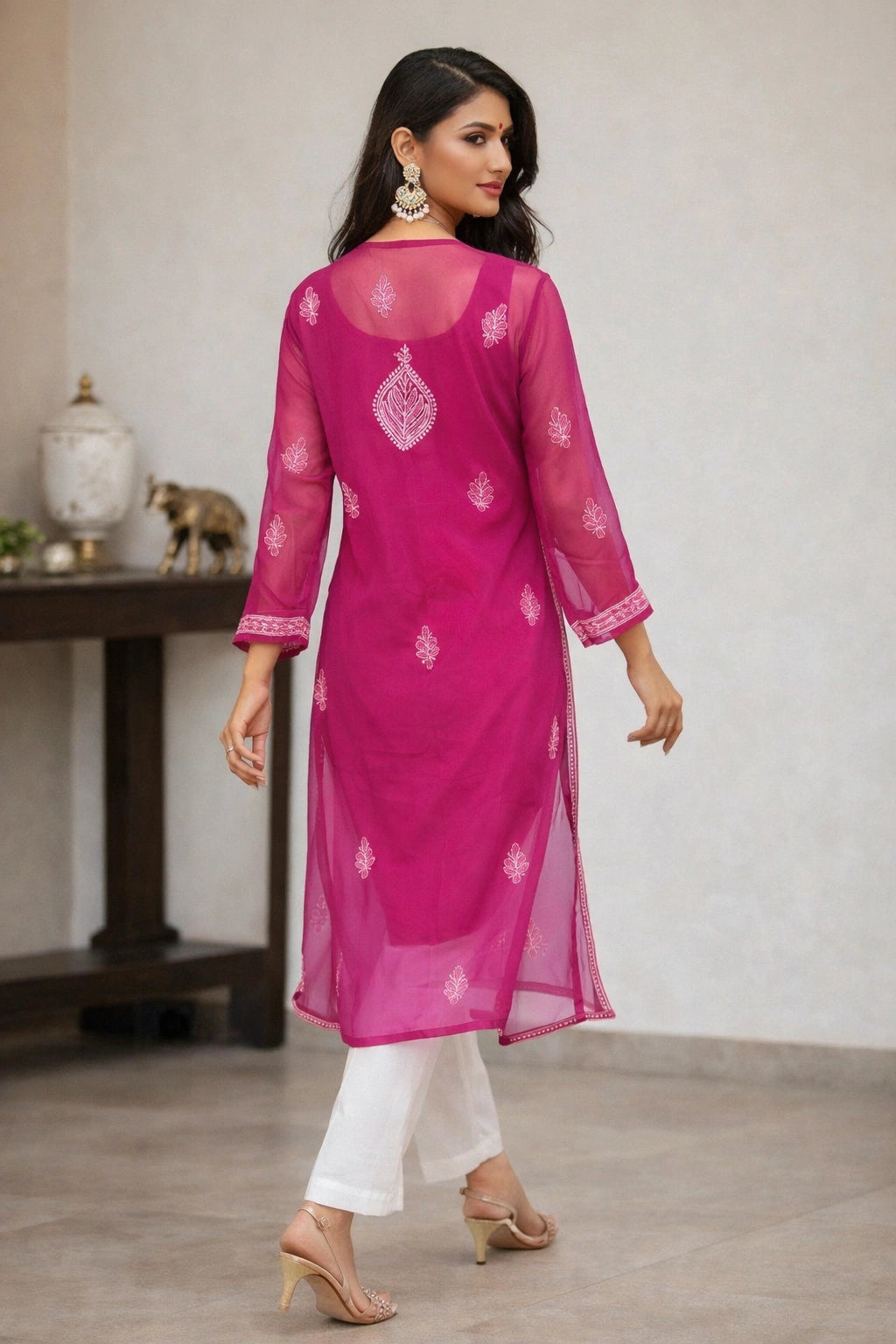 Person wearing a lucknow chikankari  magenta kurta with gold embroidery in front 