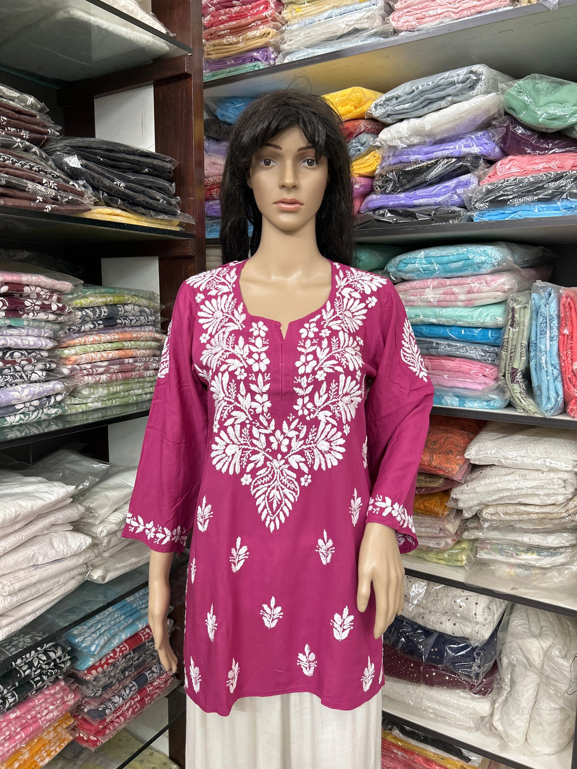 Mannequin wearing a pink embroidered top in a fabric store