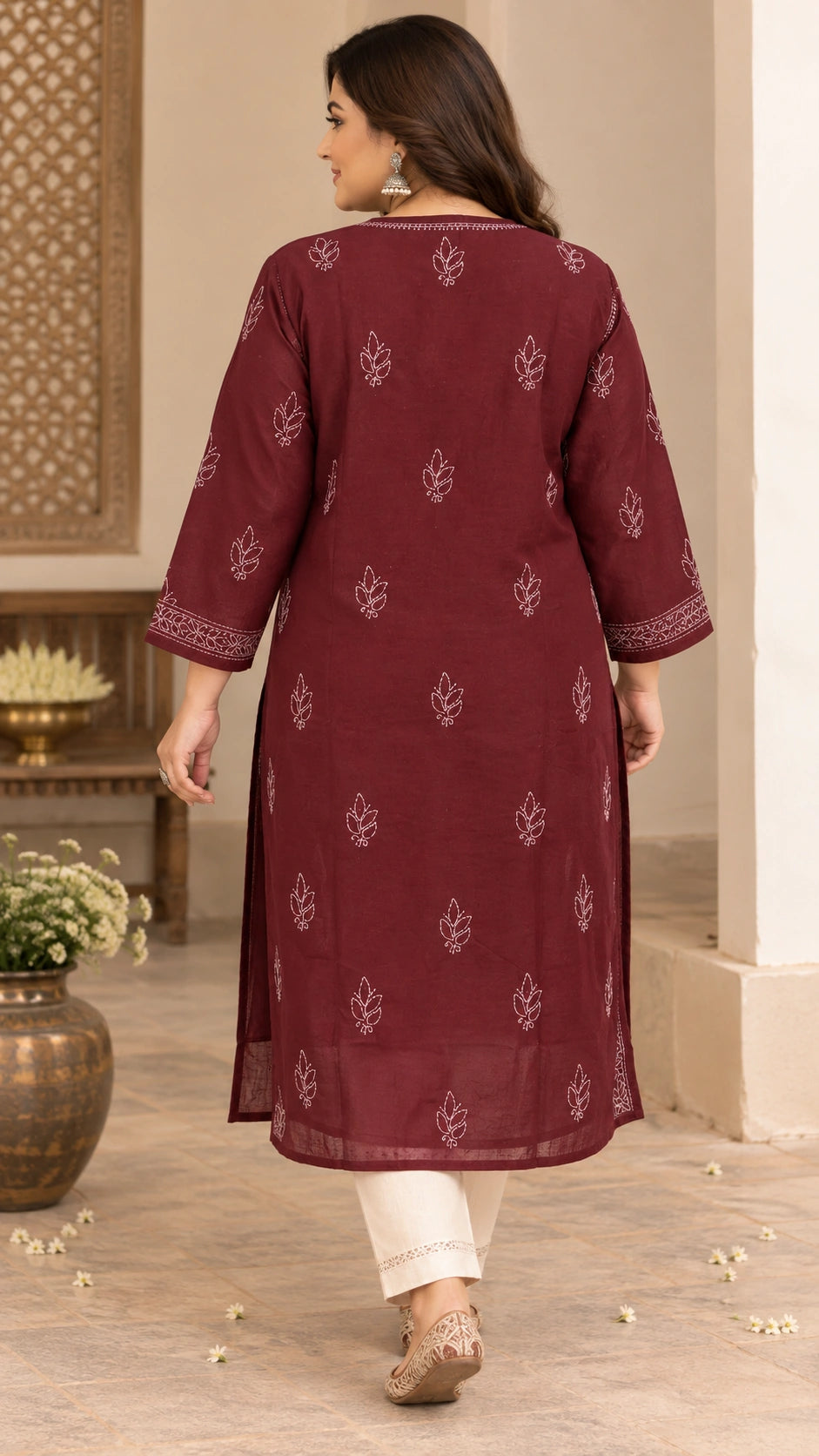 A woman shown from the back wearing a maroon three-quarter sleeve kurta with white leaf and border prints, paired with off-white pants and beige flat shoes, in an indoor setting.