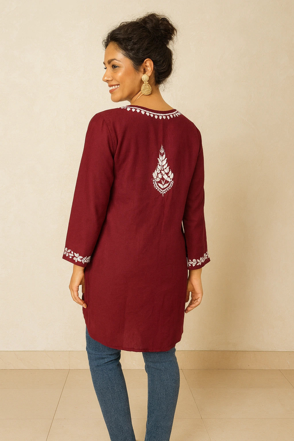 Woman wearing a maroon kurta with white embroidery on a beige background
