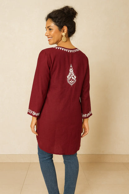 Woman wearing a maroon kurta with white embroidery on a beige background