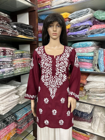 Mannequin wearing a maroon embroidered top in a fabric store.