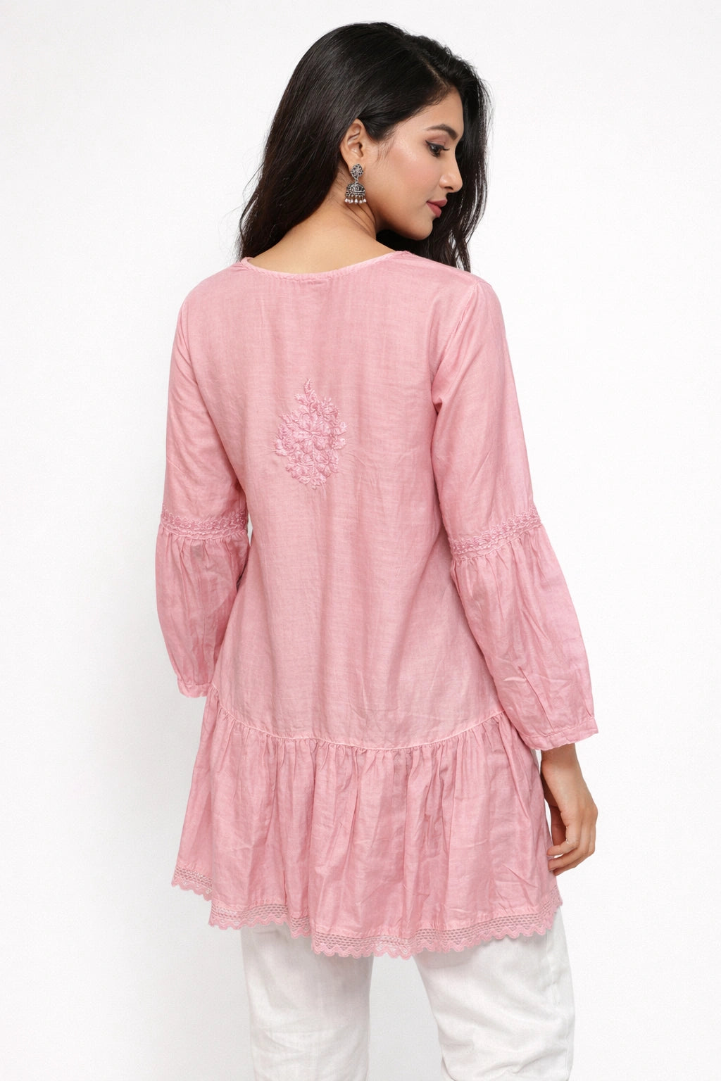 Woman wearing a lucknowi chikankari pink long-sleeve top with white pants on a white background