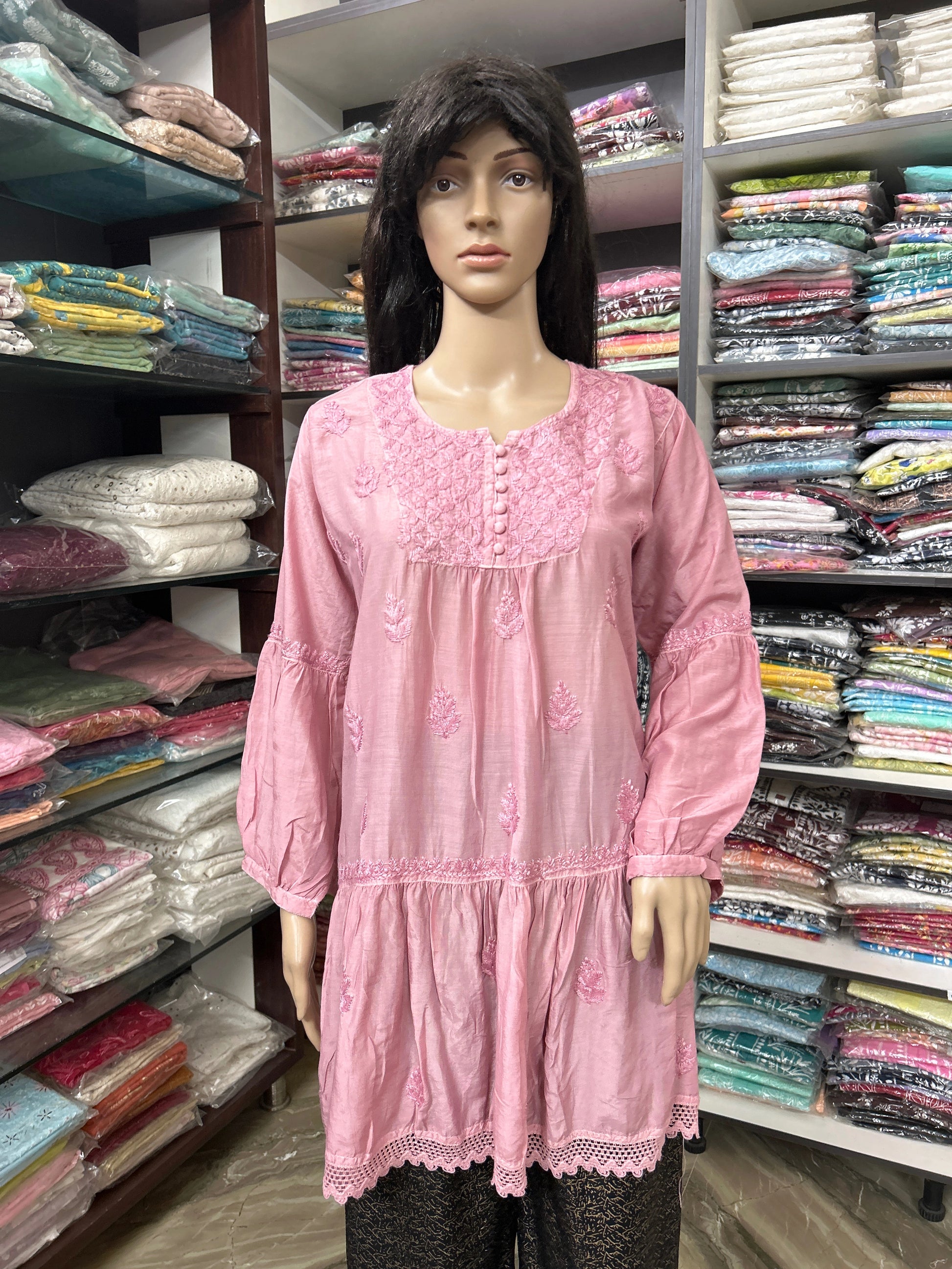 Mannequin wearing a pink embroidered dress in a fabric store
