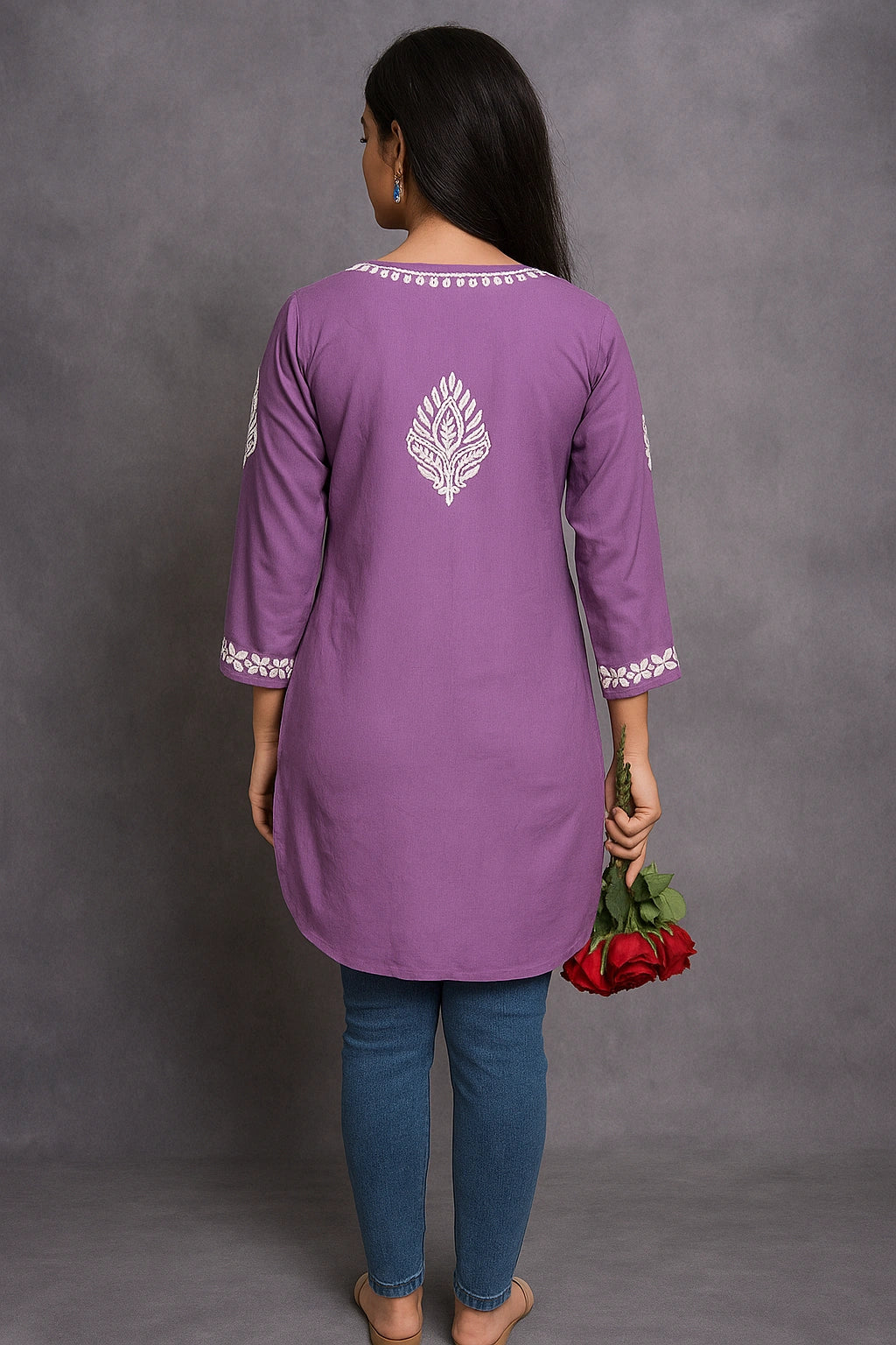 Person wearing a purple kurta with white embroidery, holding red roses against a gray background