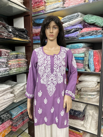 Mannequin wearing a purple embroidered top in a fabric store