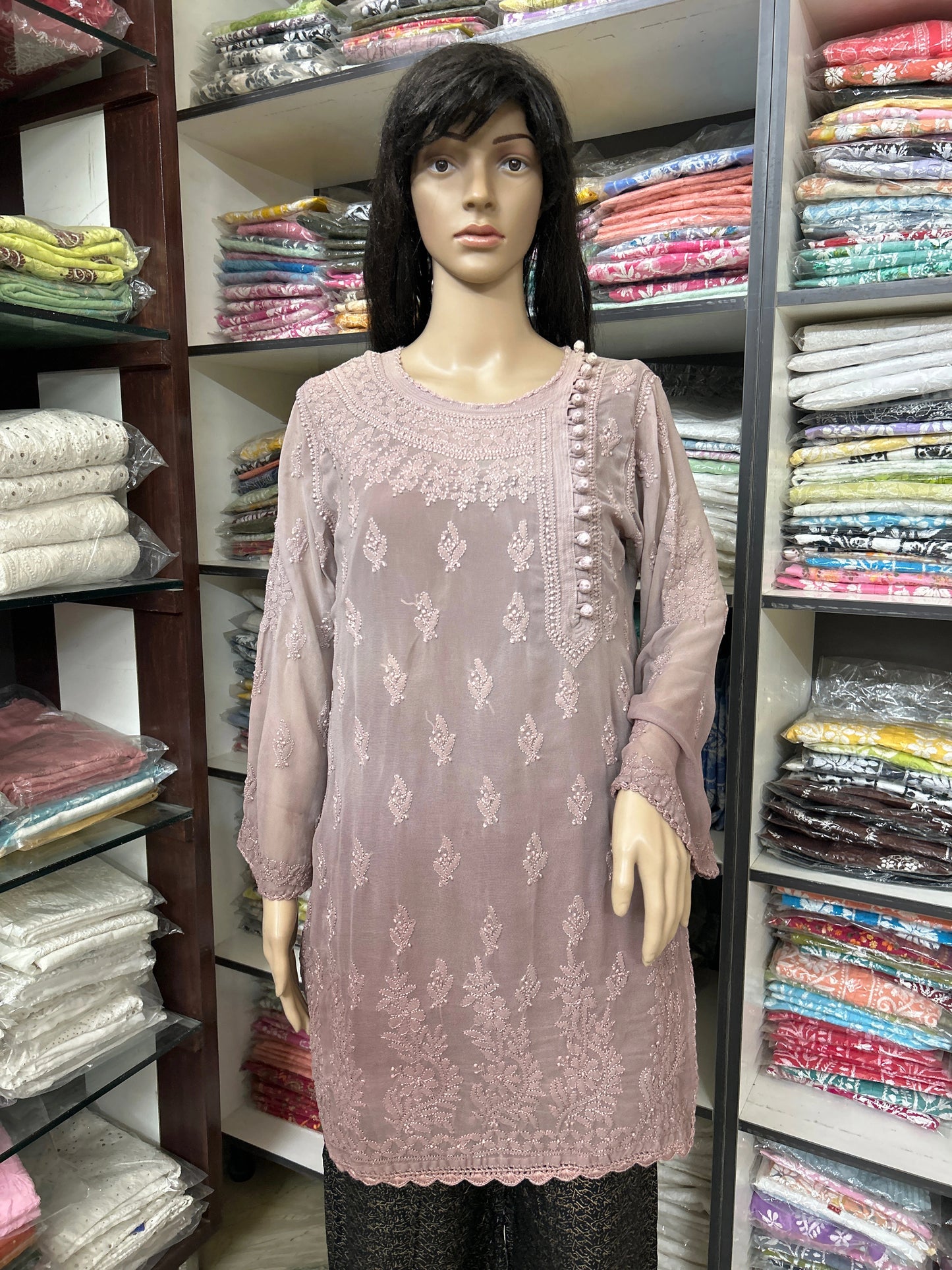 Mannequin wearing a mauve embroidered top in a fabric store