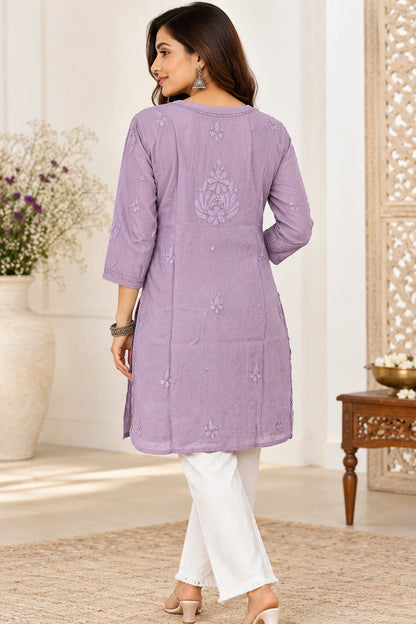 Woman wearing a lucknowi chikankari  mauve kurta with white floral patterns 