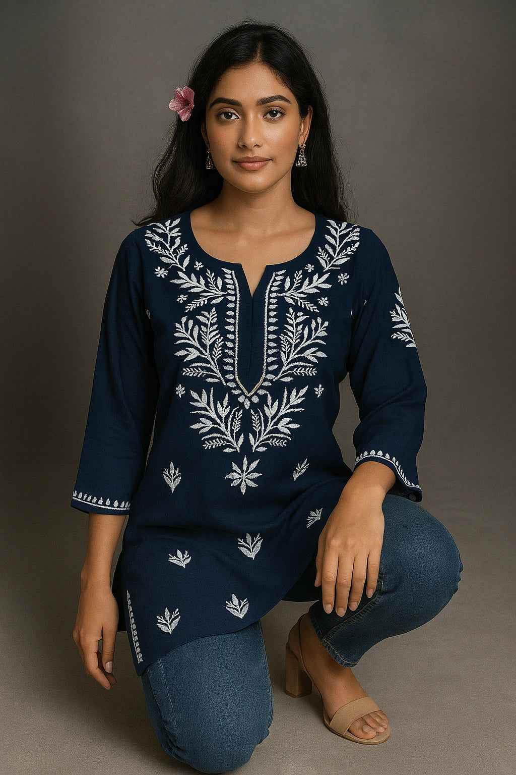 Woman wearing a navy blue embroidered outfit on a gray background