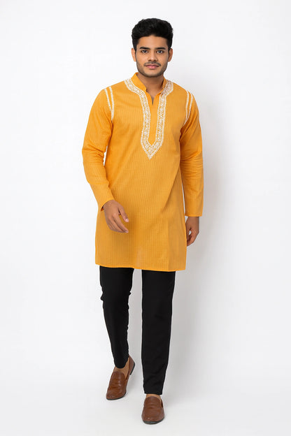 Man wearing a lucknowi chikankari mustard yellow kurta with black pants on a white background