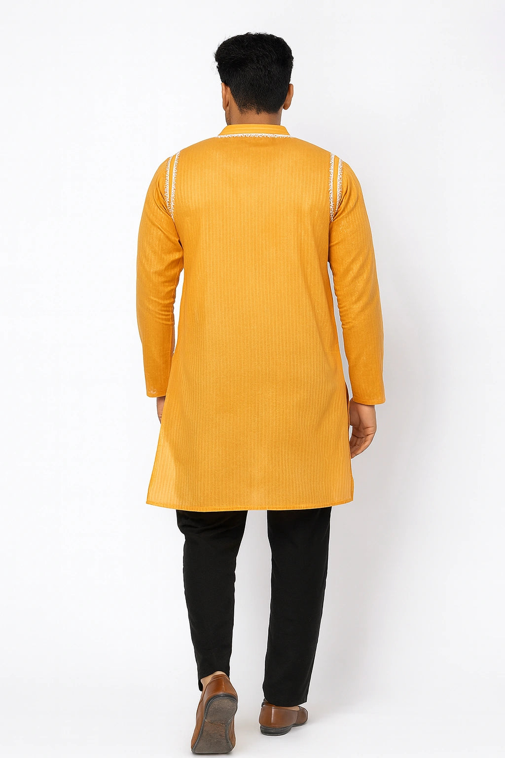 Person wearing a  lucknowi chikankari yellow kurta with black pants on a white background