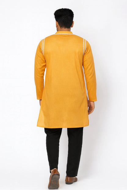 Person wearing a  lucknowi chikankari yellow kurta with black pants on a white background