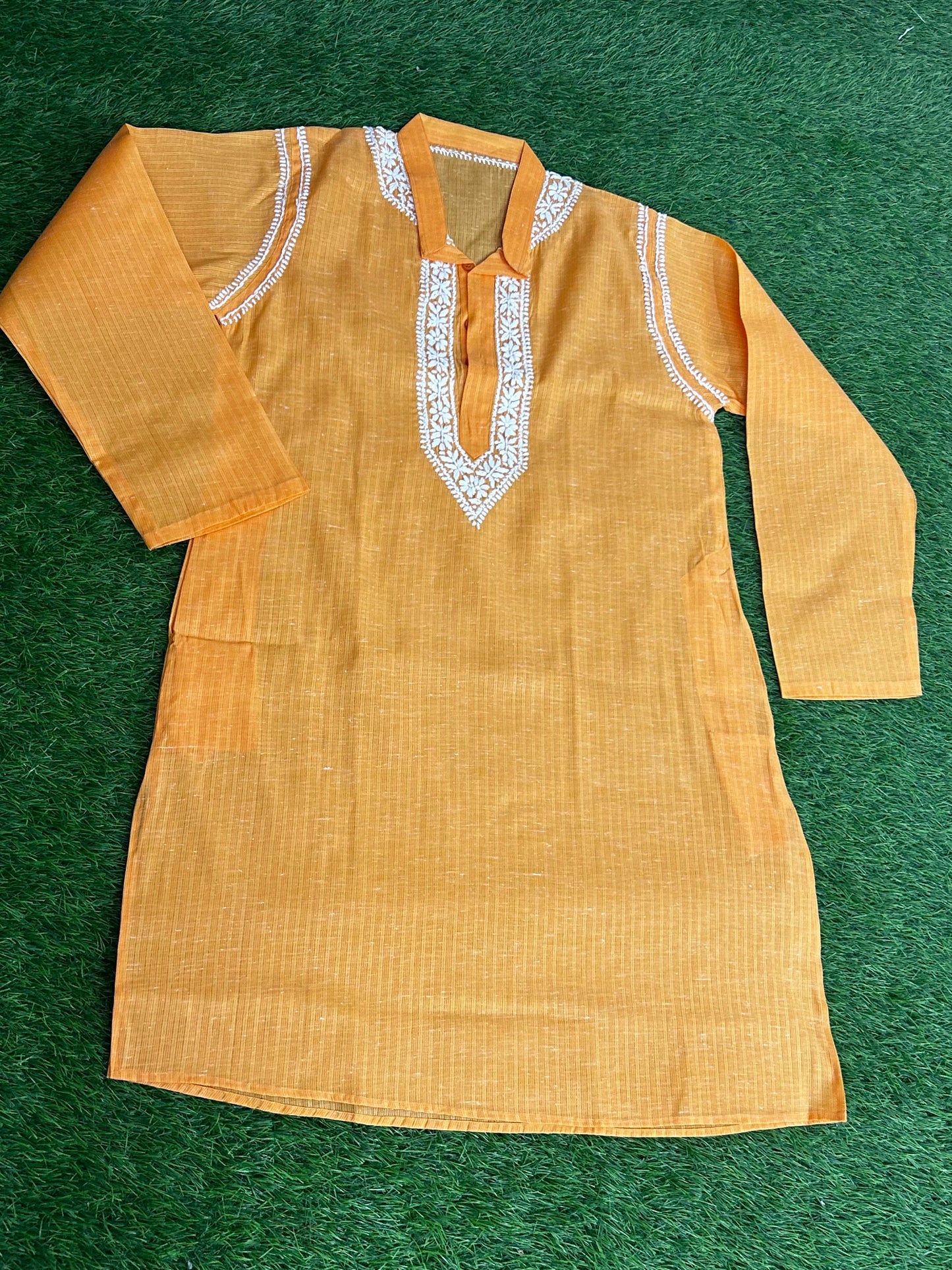 Yellow kurta with white embroidery on a green background