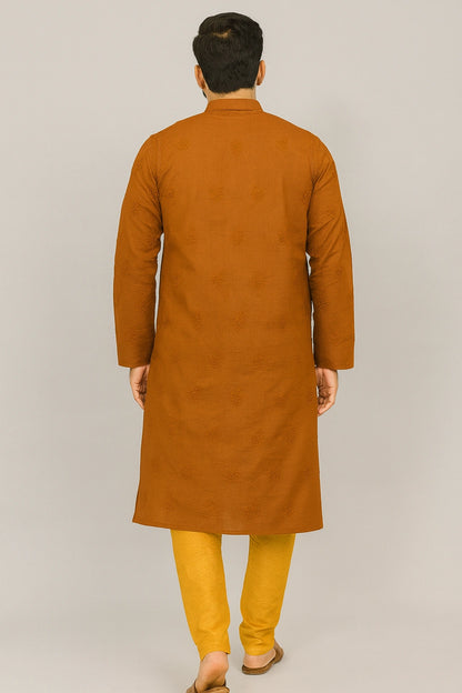 Lucknowi chikankari A man viewed from behind wearing a long-sleeved mustard-brown kurta paired with yellow trousers, standing against a plain light gray studio background.