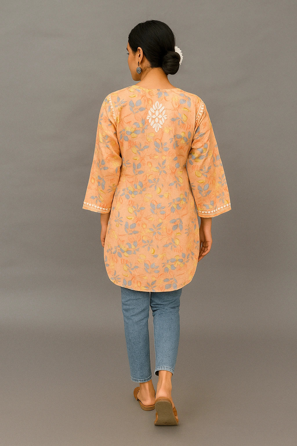 lucknowi chikankari Woman wearing an orange floral patterned kurta with blue jeans on a gray background