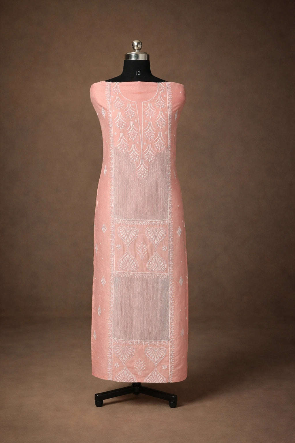 Pink dress with white embroidery on a mannequin against a brown background