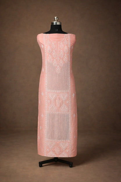 Pink dress with white embroidery on a mannequin against a brown background