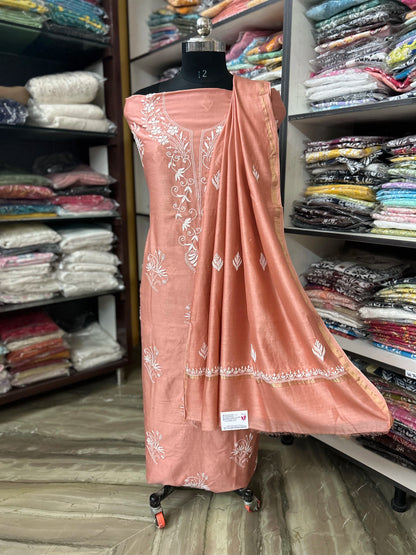 lucknowi chikankari Peach-colored dress with white patterns on a mannequin in a fabric store.