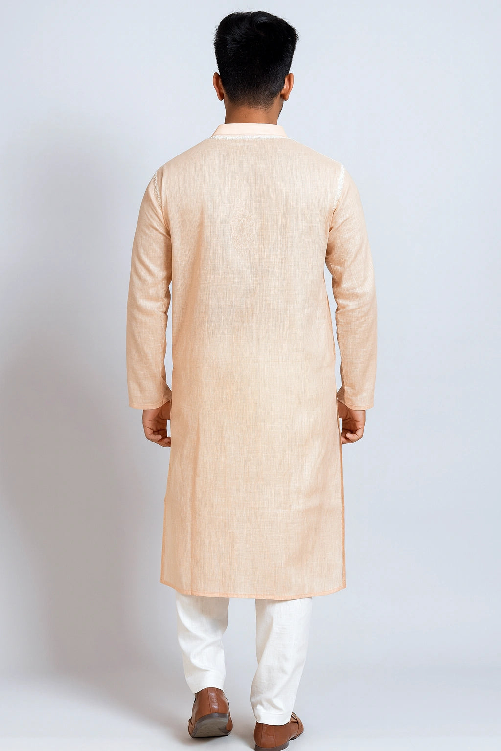 Man wearing a lucknowi chikankari beige kurta with white pants on a light gray background