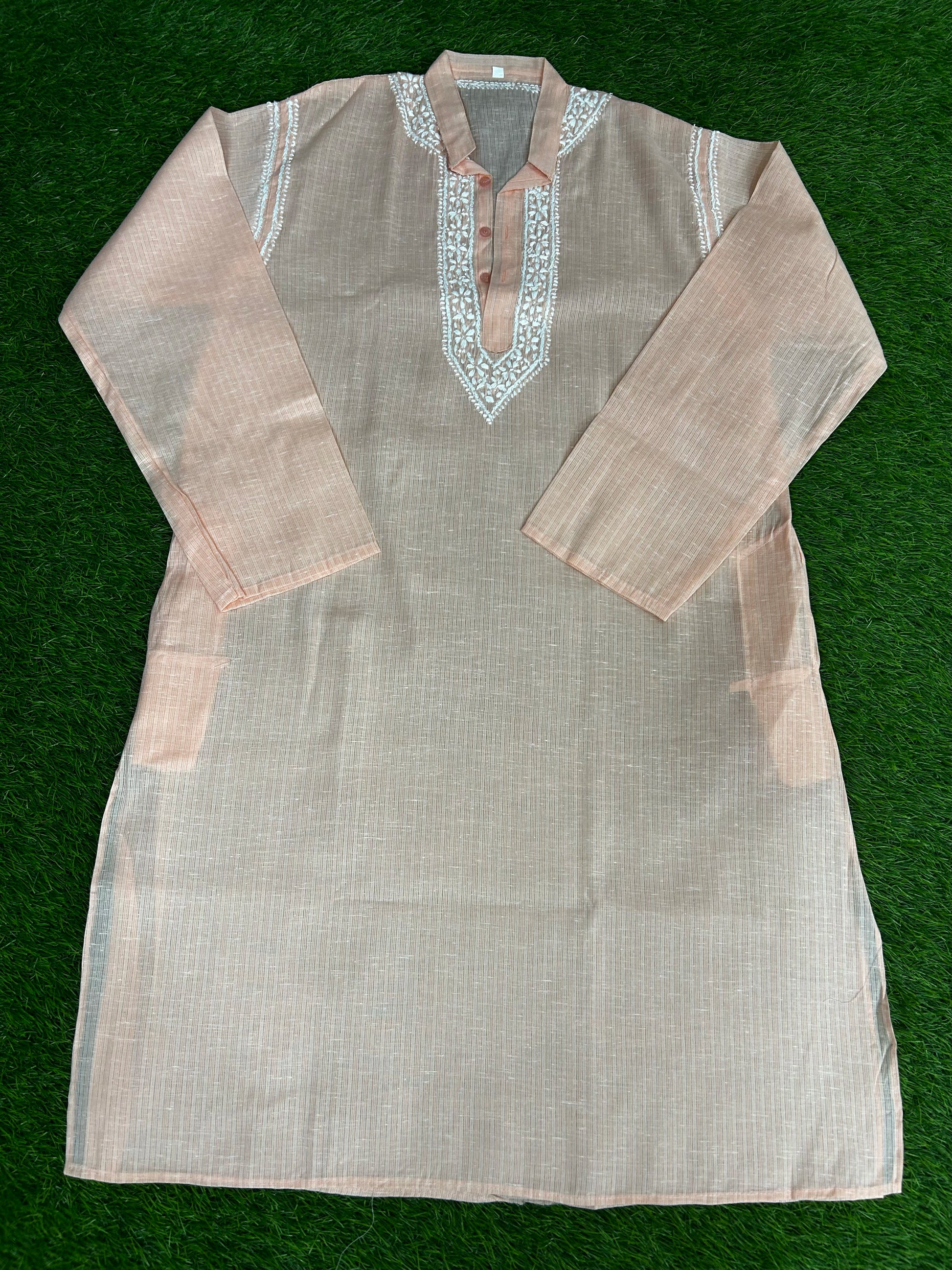 Light brown kurta with intricate white embroidery on a green background