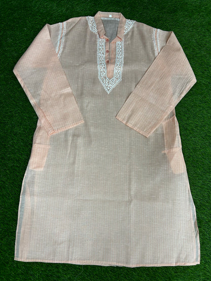 Light brown kurta with intricate white embroidery on a green background