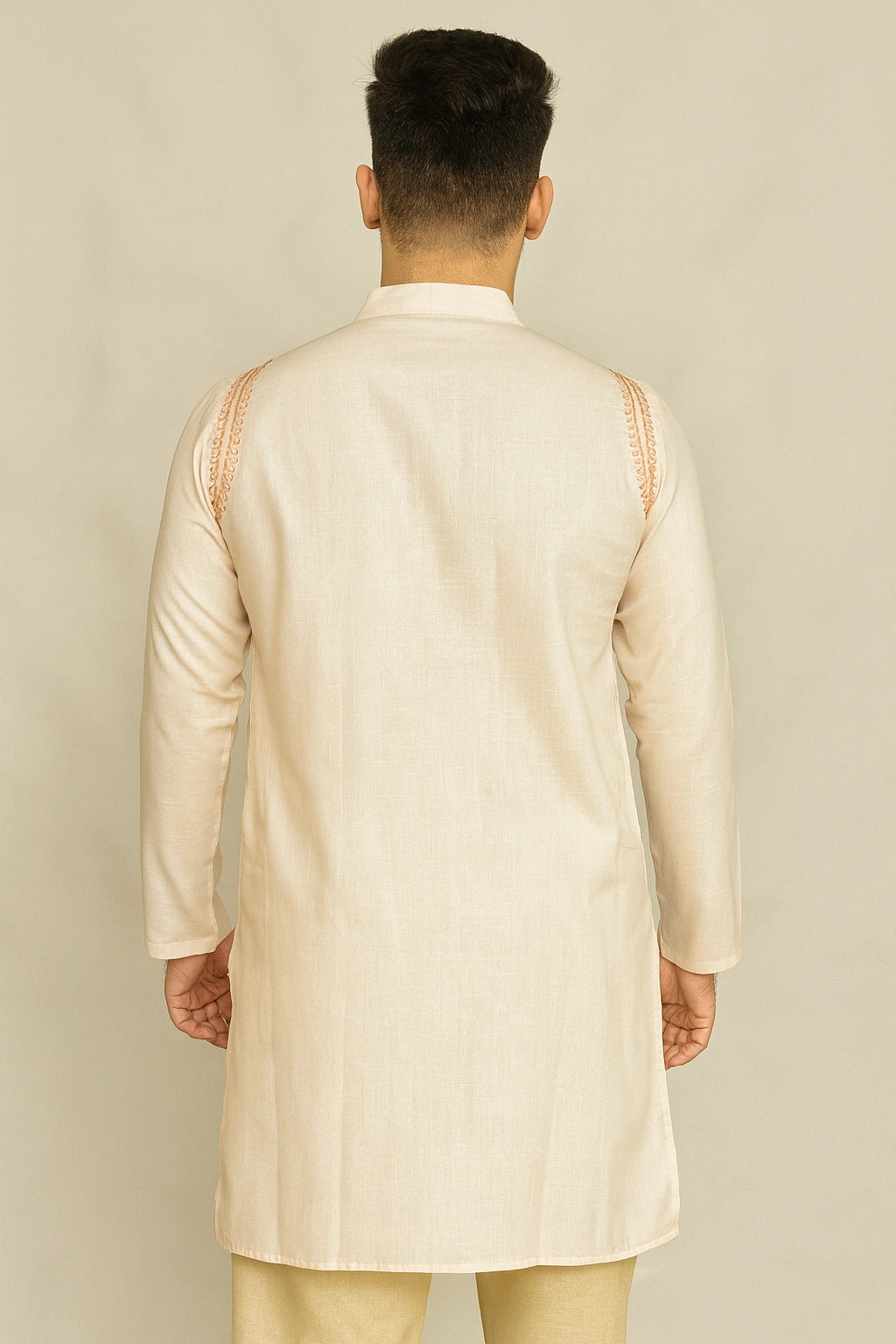 Man wearing a lucknowi chikankari beige kurta with intricate detailing on a plain background
