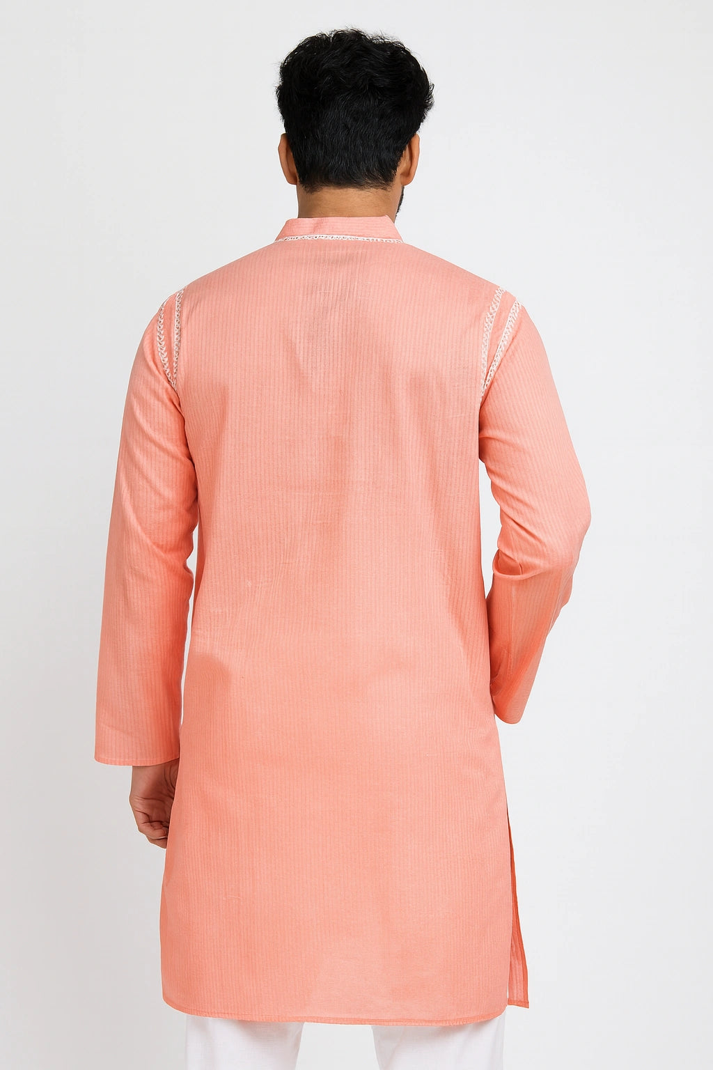 Person wearing a peach kurta with white pants on a light gray background
