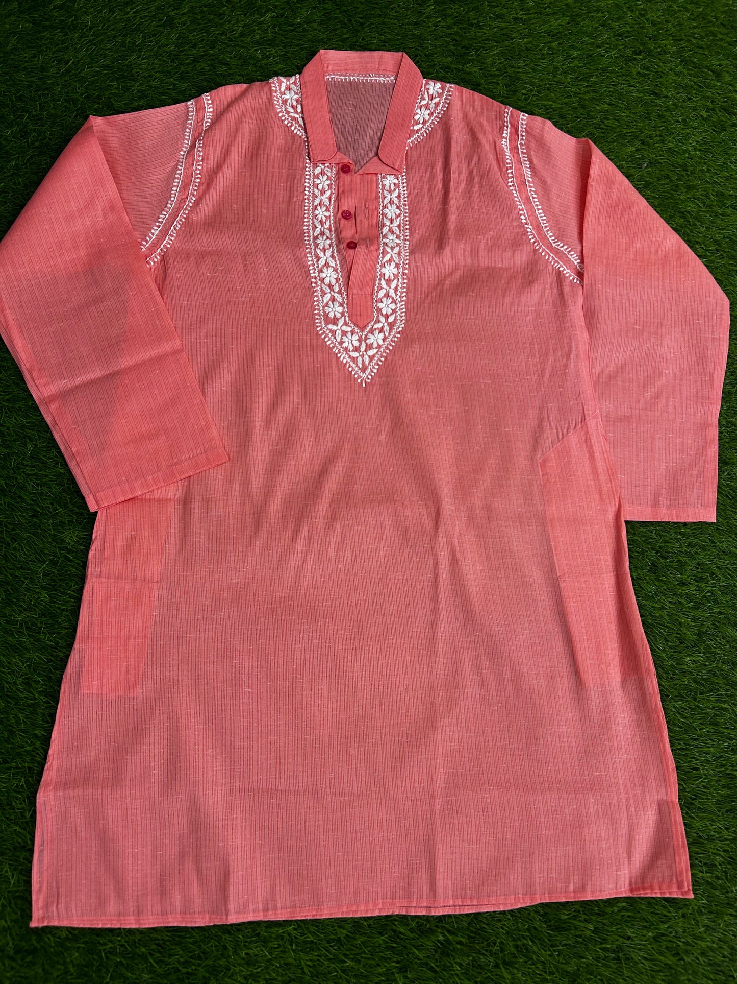 Pink garment with white embroidery on a green background